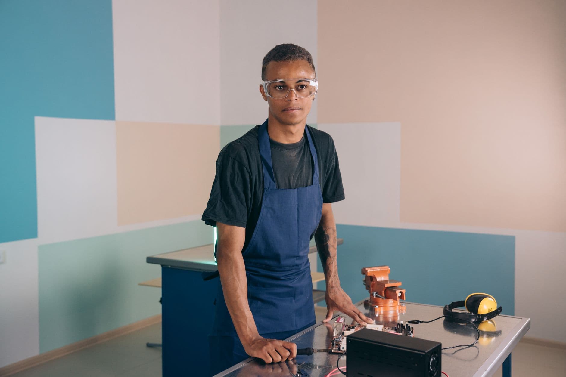 Persona joven con gafas de proteccion y delantal en un taller de formacion