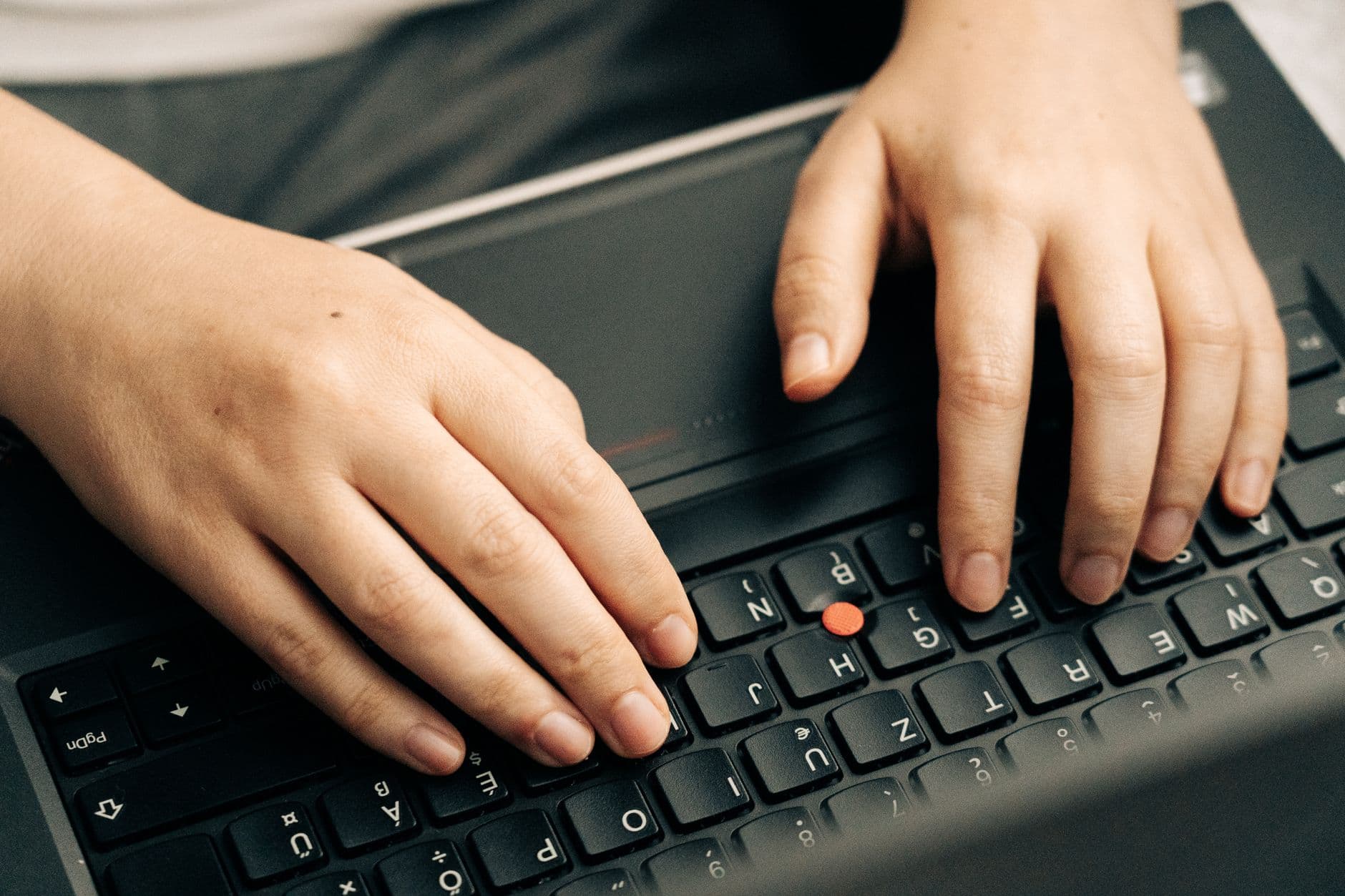Manos escribiendo en el teclado de un ordenador portatil