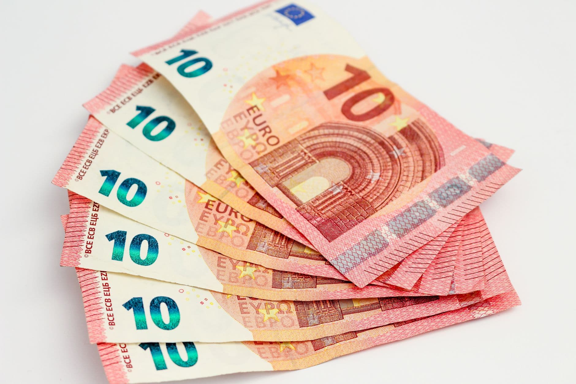 Varios billetes de diez euros abiertos en abanico sobre un fondo blanco.
