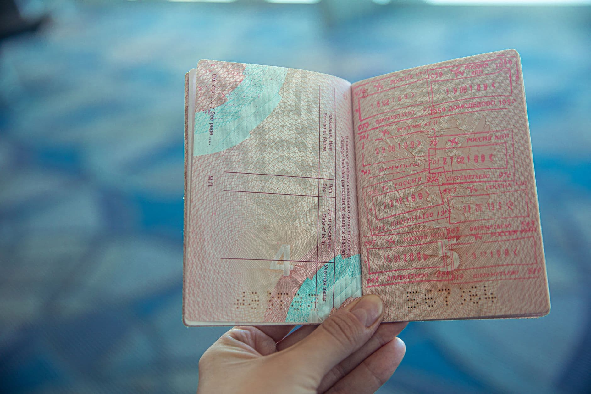Manos sosteniendo un pasaporte abierto con sellos de entrada
